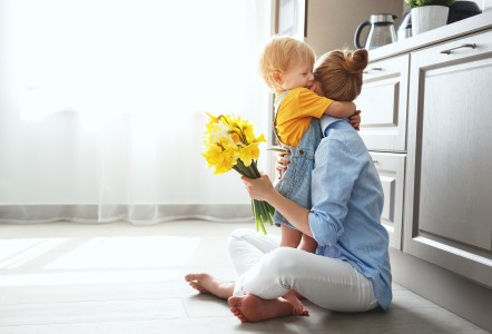 Mutter sitzt auf Boden und hält ihr Kind im Arm