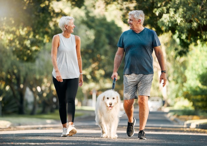 Paar in Sportkleidung unternimmt Spaziergang mit Hund
