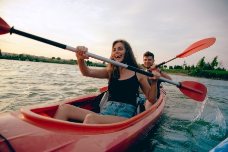 Zwei Personen die in Paddelboot sitzen und lachen