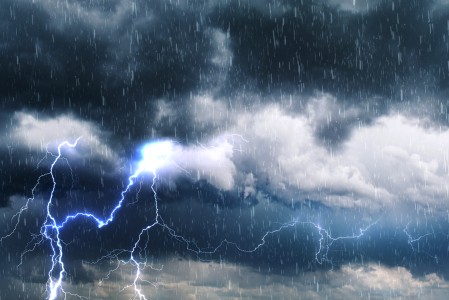 Es sind graue, dunkle Wolken, Regen und Blitze zu sehen.
