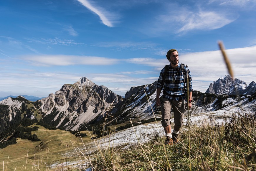Ein Mann wandert auf einem Berg mit Steinen und Gras.