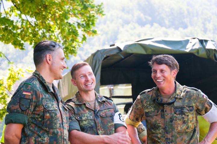 Drei Männer in Militärkleidung unterhalten sich lachend.