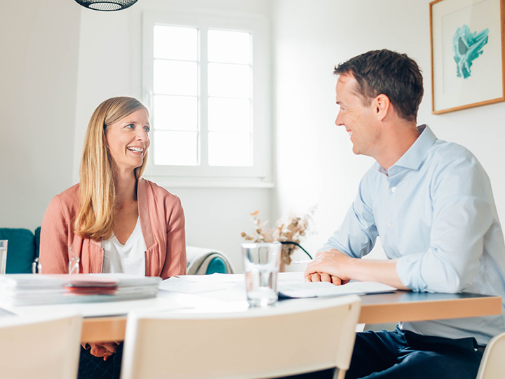 Julia und Clemens Reusch sitzen an einem Tisch und führen ein Gespräch