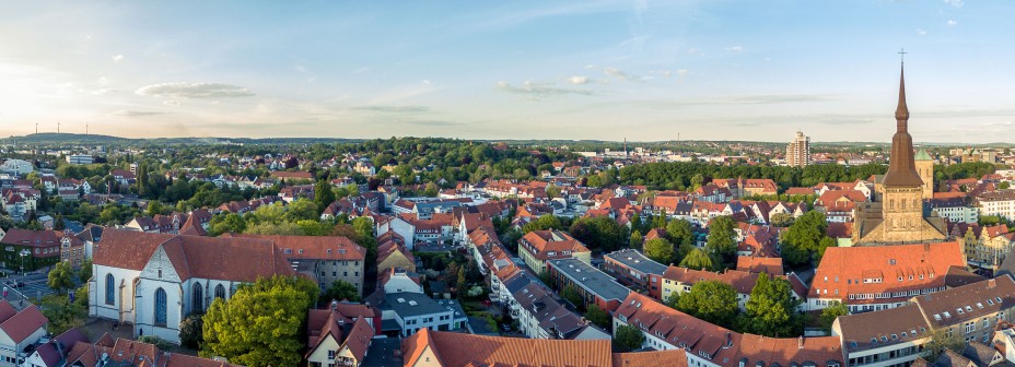 Blick auf Osnabrück, historische Gebäude sind erkennbar sowie Wohngebäude und ähnliches. Her Himmel hat ein paar Wolken und die Sonne schein