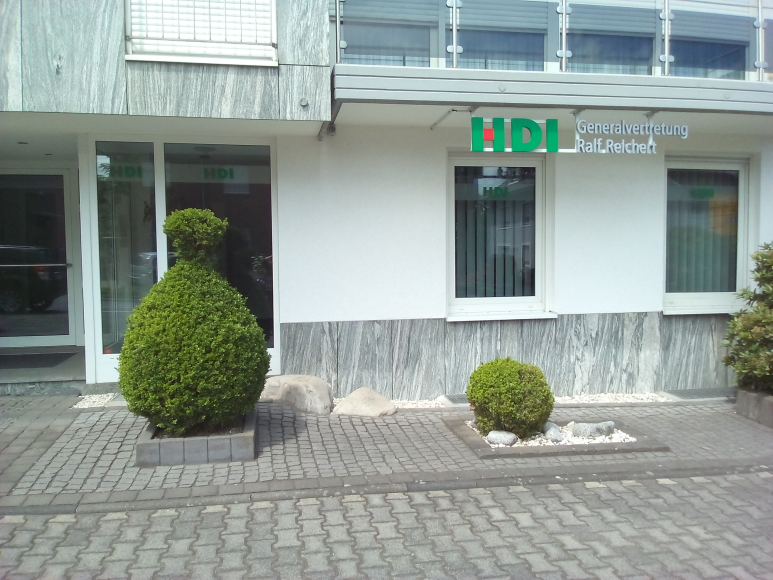 weißes Haus der HDI Agentur vor dem drei Büsche stehen