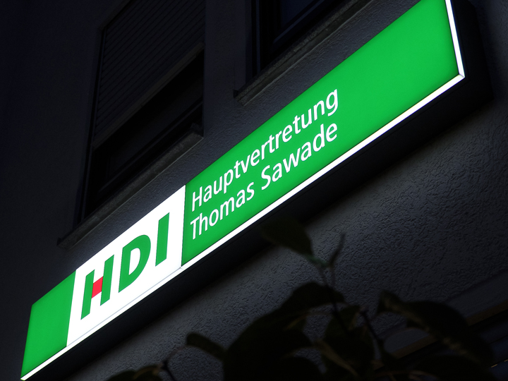 grünes Agenturschild bei Nacht mit der Aufschrift HDI Hauptvertretung Thomas Sawade