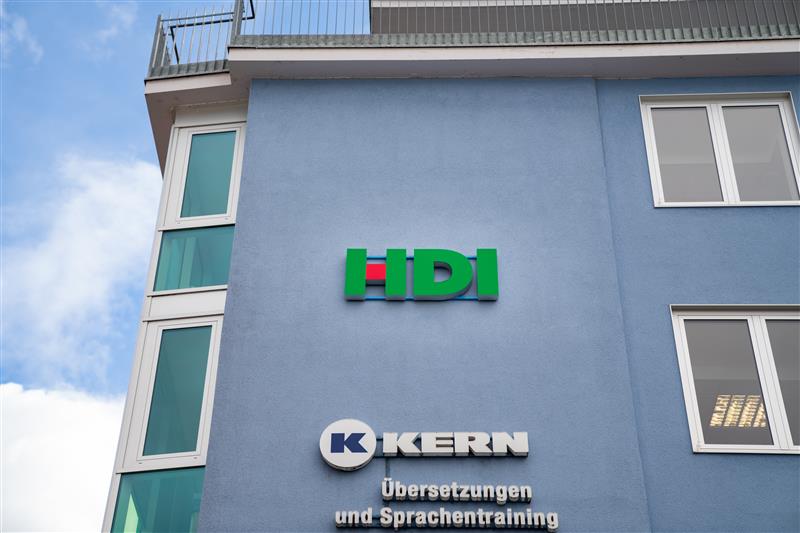 das HDI Logo ist an einer blauen Hauswand befestigt.