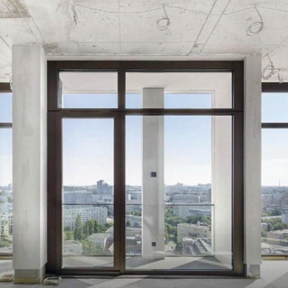 Blick auf eine Großstadt aus der Fensterfront einer großen modernen Penthouse-Wohnung im Rohbauzstand