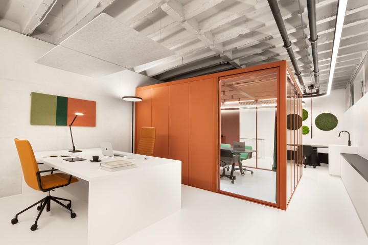 Modernes, minimalistisches Büro mit zwei gegenüberstehenden Schreibtischen, Schreibtischstühle und ein großer Aktenschrank in orange und schwarzen Deisgnerlampen, ein macbook steht auf einem Schreibtisch