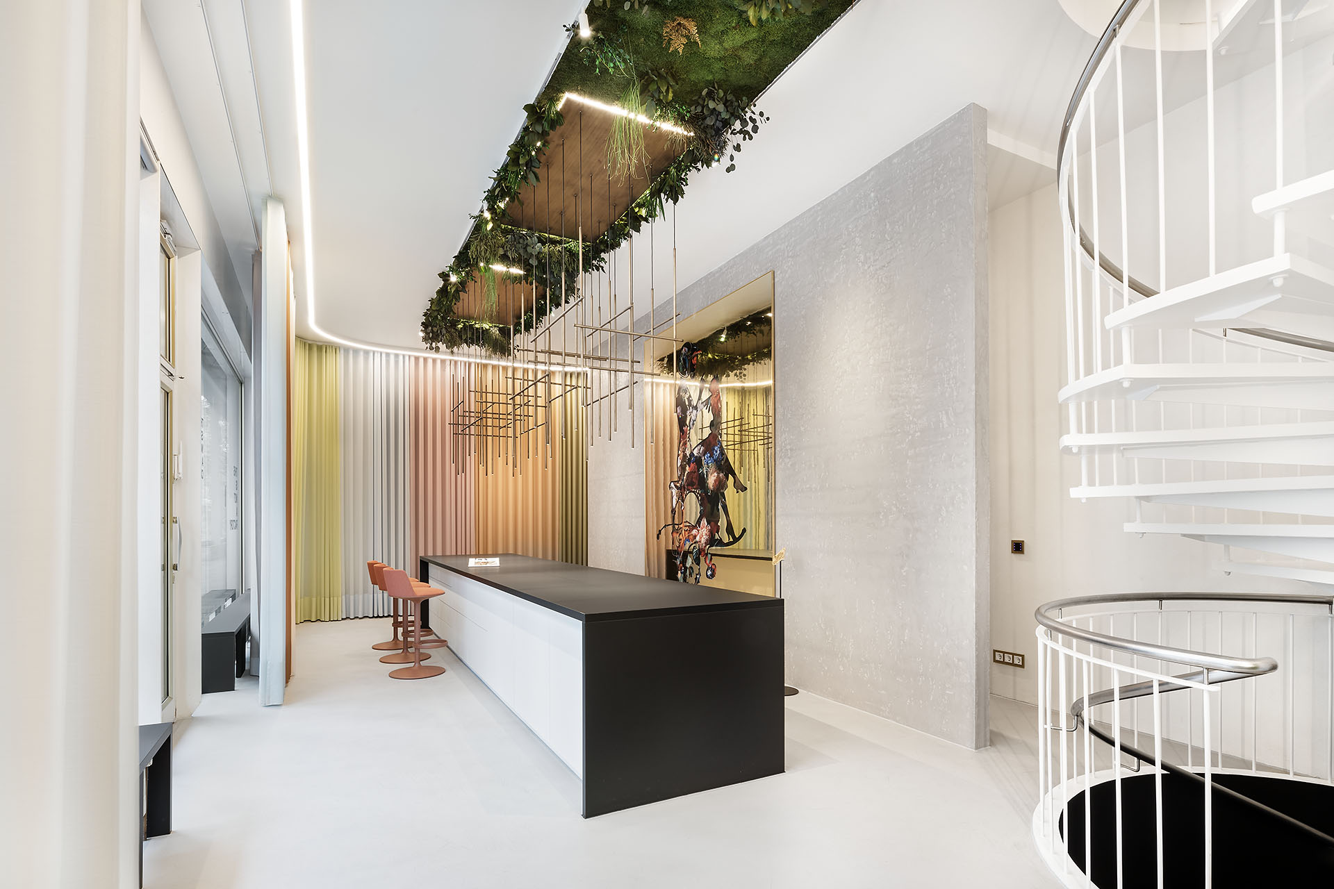 Modernes Büro mit weißen Möbeln, einer weißen Wendeltreppe und Pflanzen, die von der Decke hängend wachsen