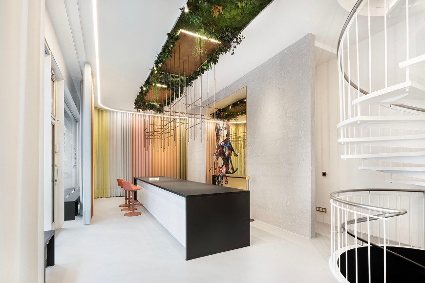 Modernes Büro mit weißen Möbeln, einer weißen Wendeltreppe und Pflanzen, die von der Decke hängend wachsen
