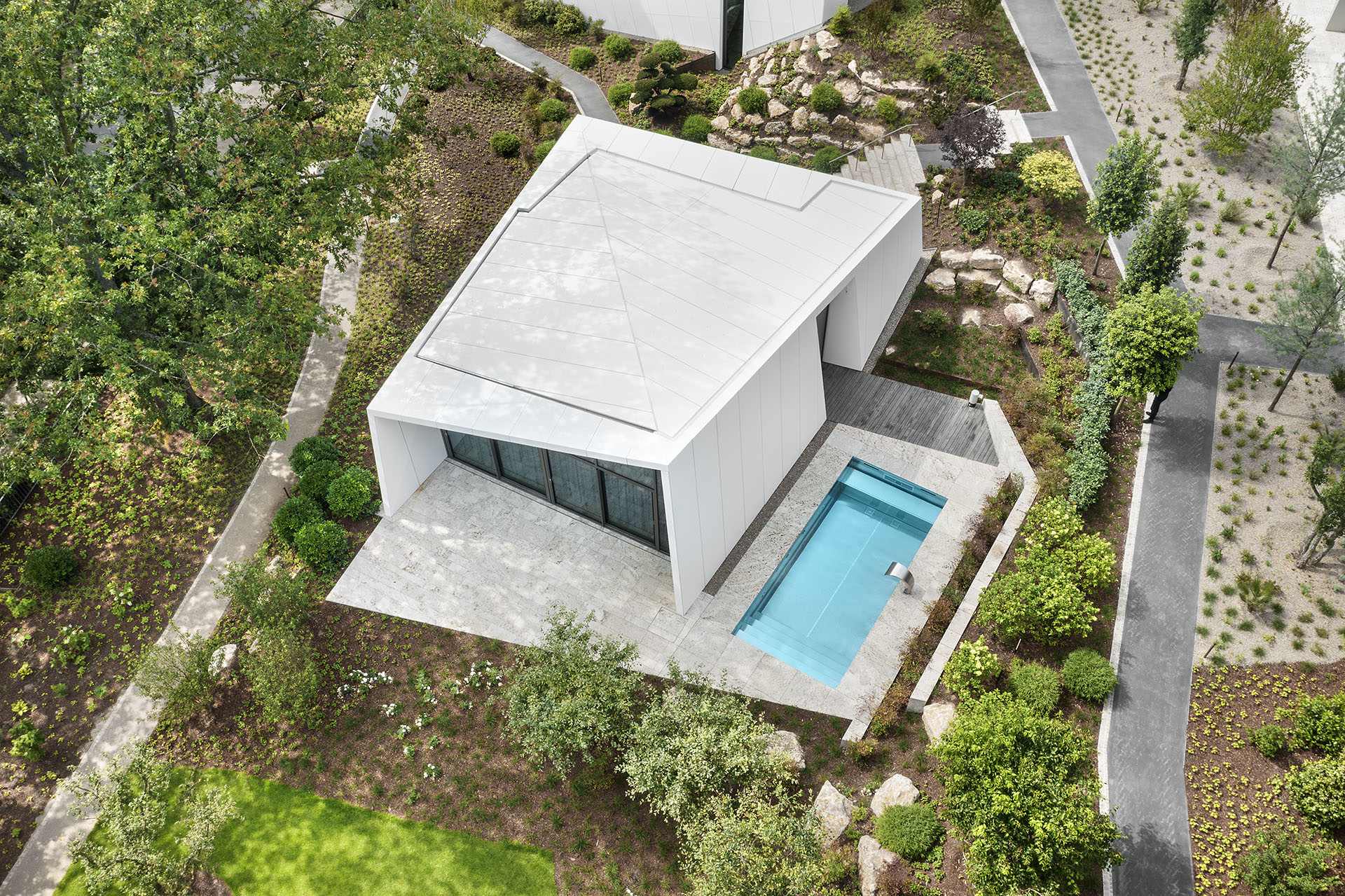 Luftaufnahme mit Blick senkrecht auf futuristische weiße Bungalow in einer mordernen Gatrneanlage mit rechteckigigem Pool