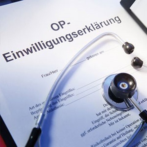 Quadratisches Bild, auf dem man einen Zettel sieht, auf dem OP-Einwilligungserklärung steht, quer über dem Zettel liegt ein Stethoskop
