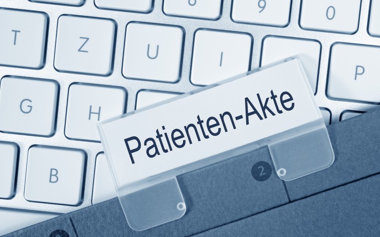 weiße Tastatur und darauf eine Akte mit einem Schild Patientenakte