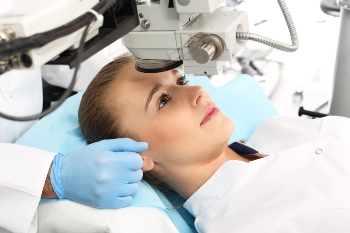 Blonde Frau liegt auf einem Behandlungstisch unter einem Augenlaser