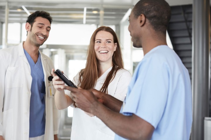 Drei im Gesundheitswesen tätige Personen reden in der Empfangshalle eines Krankenhauses miteinander.