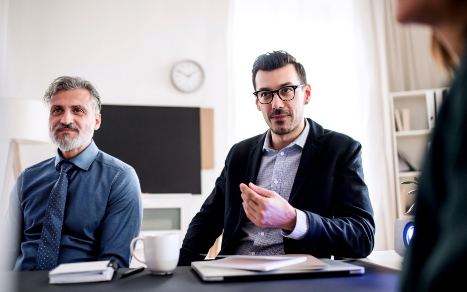 Drei Berater sitzen zusammen in einem Büro am Konferenztisch und besprechen etwas