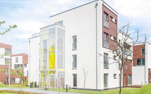 Außenansicht eines modernen Mehrfamilienhauses in einer Wohnanlage mit Grünflächen im Vordergrund