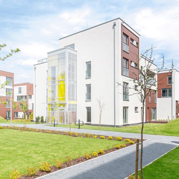 Außenansicht eines modernen Mehrfamilienhauses in einer Wohnanlage mit Grünflächen im Vordergrund