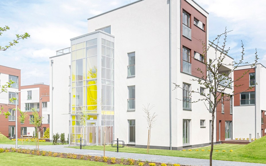 Außenansicht eines modernen Mehrfamilienhauses in einer Wohnanlage mit Grünflächen im Vordergrund