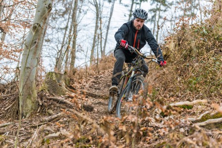 Mountainbiker fährt eine Downhillstrecke durch einen herbstlichen Wald