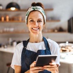 Frau mit Schürze und Tablet in der Hand