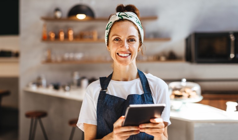 Frau mit Schürze und Tablet in der Hand