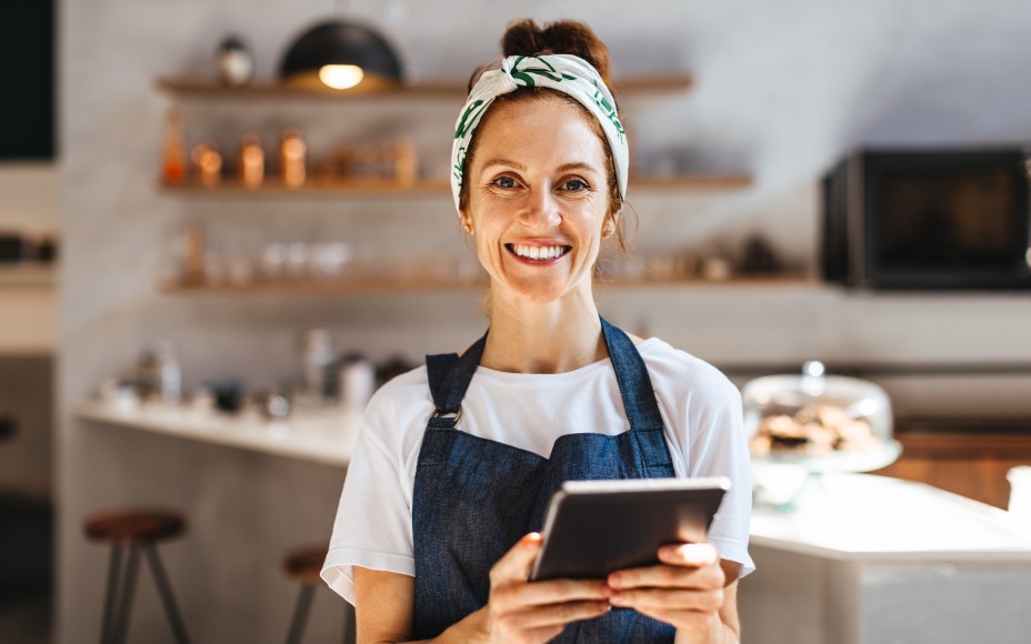 Frau mit Schürze und Tablet in der Hand