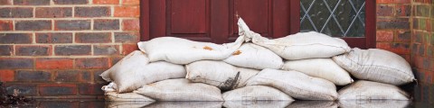 Weiße Sandsäck,e die bei Hochwasser an einem Haus aus roten Ziegelsteinen aufgestapelt sind