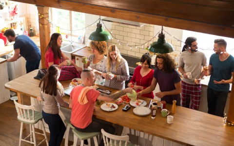 Mehrere junge Leute frühstücken in einer großen Wohnküche, vermutlich eine Studenten-WG
