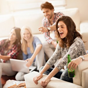 Junge Leute lachen zusammen und sitzen in einem Wohnzimmer auf Sofas