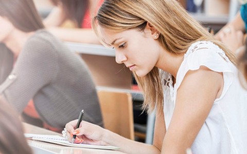 Studierende in einem Hörssal schreiben alle konzentriert etwas auf, vermutlich eine Klausir