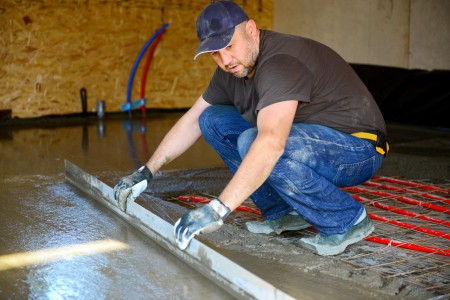 Handwerker legt Estrich auf Fußbodenheizung