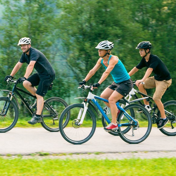 Vierköpfige Familie fährt auf Fahrrädern an einem Bergsee vorbei