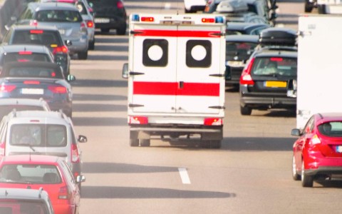 Rettungswagen fährt durch eine Rettungsgasse, die Fahrzeuge rechts und links bilden