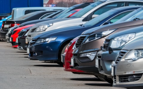 Mehrere Autos verschiedener Farben stehen nebeneinander auf einem aspahltierten Hof