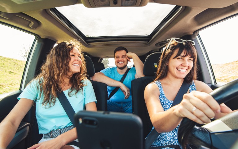 Fahrerkreiserweiterung - drei junge Leute, zwei Frauen vorne und ein Mann hinten in der Mitte, strahlen, während sie unterwegs sind