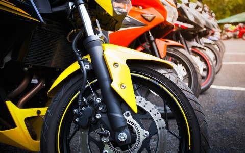 Verschieden farbige Motorräder stehen nebeneinander in einer Reihe