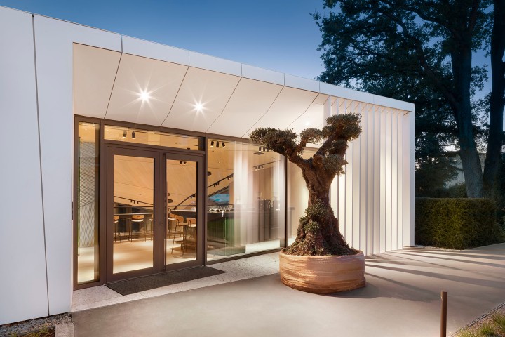 Moderne weiße Villa mit großer Glasfront und einer modernen Skulptur auf der Terrasse