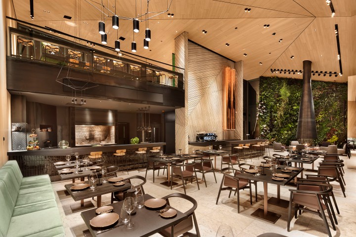 Modernes Restaurant mit Loft-Charakter, schwarzen Möbeln und linsk hellgrünen Sofas