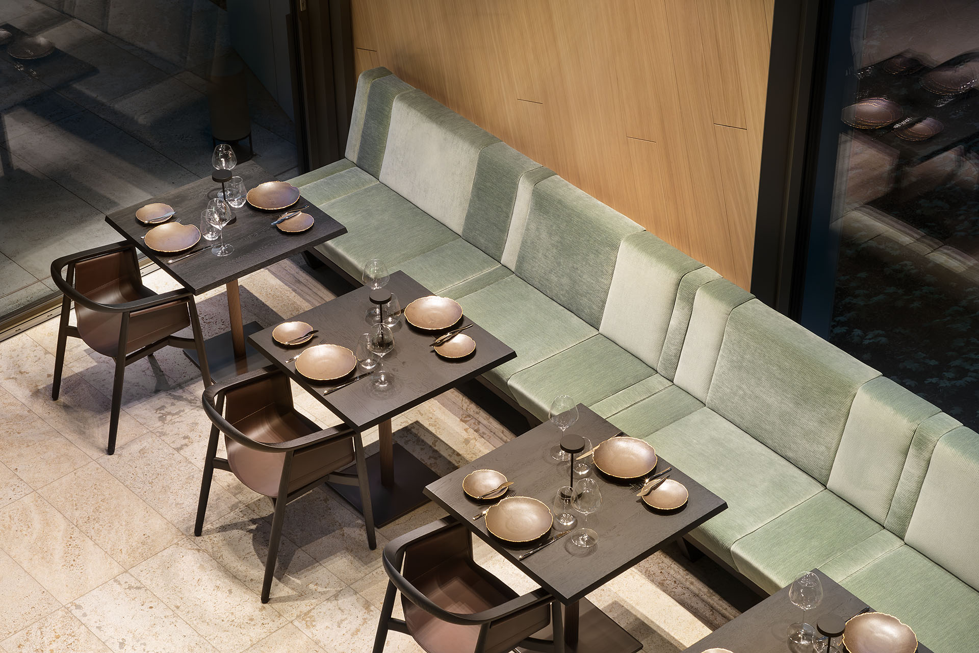 Draufsicht auf ein modernes Restaurant mit grünen Stoffsitzbänken, schwarzen Elementen in einem Raum mit Loft-Charakter