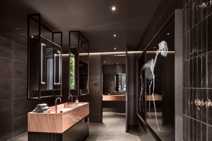 Moderner Waschraum eines Restaurants in schwarz mit Spiegeln und einem weißen Skelett als Kunstobjekt an einer Seitenwand