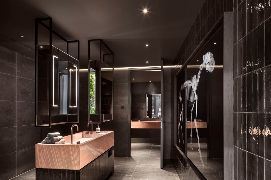 Moderner Waschraum eines Restaurants in schwarz mit Spiegeln und einem weißen Skelett als Kunstobjekt an einer Seitenwand
