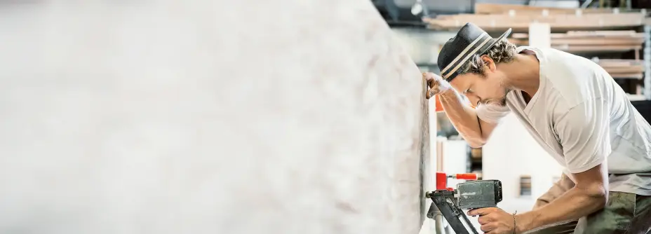 Handwerker bei der Arbeit an einem großen Werkstück in einer Werkstatt.