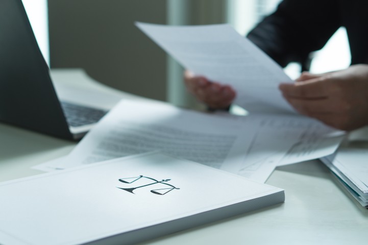 Businessmänner um einen Tisch mit Unterlagen, man sieht nur Arme und Hände