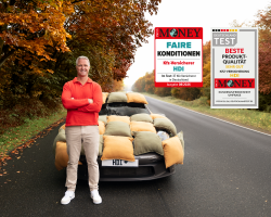 Ralf Schumacher steht grinsend vor einem mit Kissen ummantelten Auto auf einer herbstlichen Landstraße. Daneben sind zwei Siegel von Fokus Money. Das eine Siegel zeichnet den Kfz-Versicherer HDI im Test mit 37 Kfz-Versicherern in Deutschland für faire Konditionen aus. Das andere Siegel zeichnet die HDI KFZ-Versicherung basierend auf einer Kundenzufriedenheit Umfrage für Beste Produkt-Qualität mit der Note "sehr gut" aus.