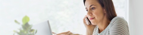 Frau am Laptop telefoniert mit dem Handy