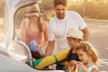 Familie mit zwei jüngeren Töchtern lädt eine Strandausrüstung in den Kofferraum ihres silbernen Autos
