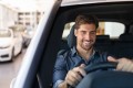 Männlicher Fahrer in einem weißen Auto sitzt am Steuer, das sich auf der rechten Seite befindet
