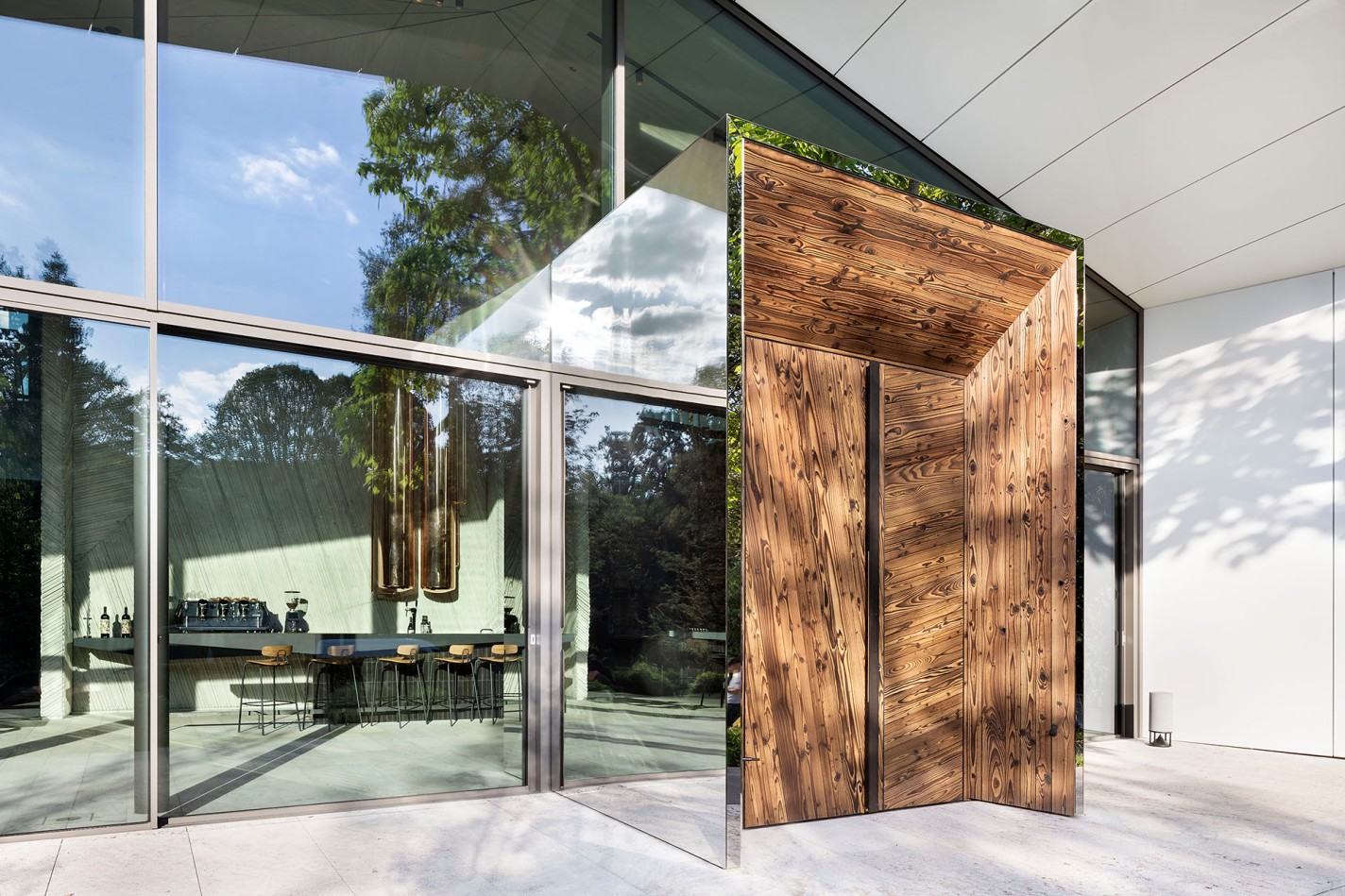 Große Fensterfront mit einer hoehn modernen Eingangstür aus Holz